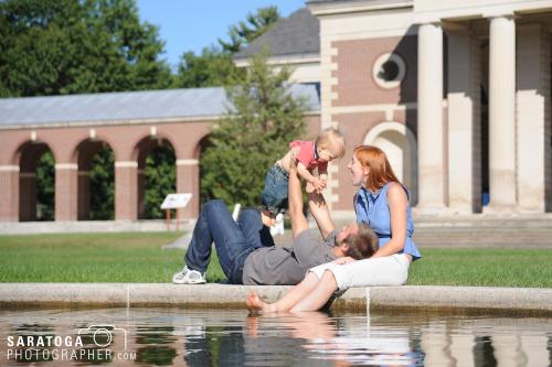 Young couple playing with toddler at reflecting pool in Saratoga spa State Park