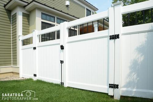 White 7 foot tall plastic Asko fence with gate next to house with green lawn