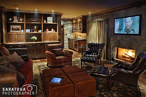 Interior of man cave showing hard wood built in cabinets stone work and plush seating