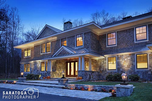 Twilight view of home with stone and cedar shingle facade