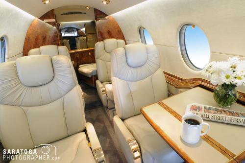 Photo showing inside of corporate jet with plush leather seats, flowers, and coffee