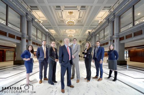 Eight Albany New York law firm attorneys with determined looks  standing in large ornate open space