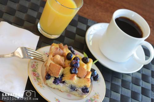 Looking down from overhead at breakfast table set with coffee orange juice and blueberry kuchen.