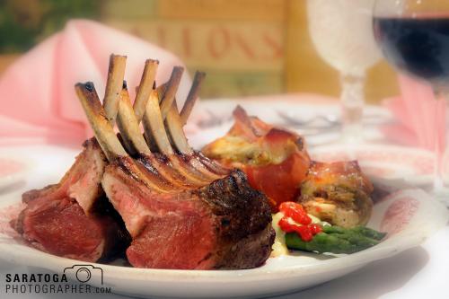 Soft focus view of table setting with plated lamb chops in for ground