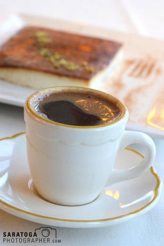 Mug of rich black coffee and foreground slice of tiramisu dessert and background out of focus