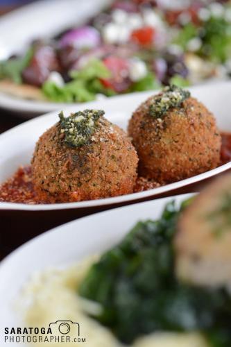 Two baked Italian meatballs in serving dish with foreground and background out of focus