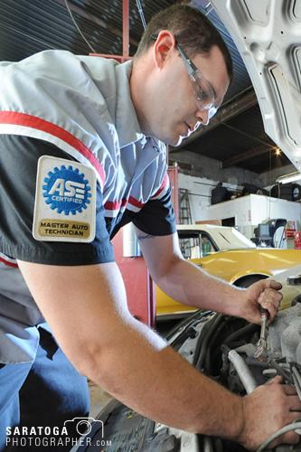 Male Auto mechanic working under hood of car