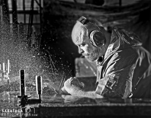 High definition high contrast black and white photo of man using grinder with dust flying