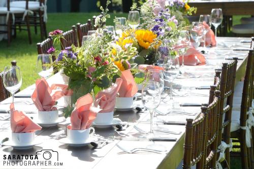Summer event dinner table laid out on lawn with silver, Crystal in many flowers