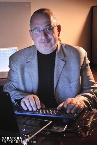 Middle aged man in blazer at computer keyboard with warm natural lighting