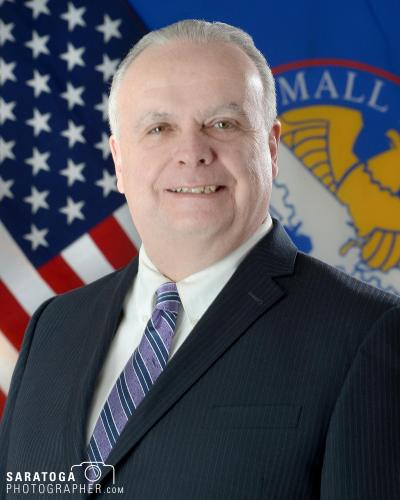 Portrait of 60 something man with suit and tie and American flag in the background