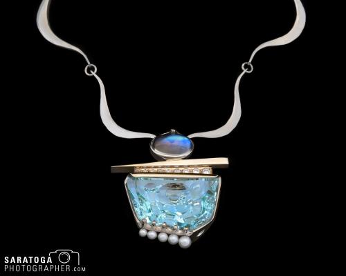 Large aquamarine necklace with moonstone set in gold with silver chain on black background