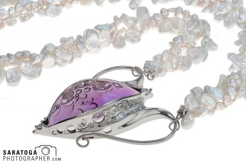 Close up of filigree on silver diamond and ruby pendant with freshwater pearl chain