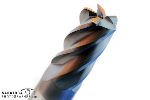 Close up view of end of Dura mill endmill 5 blade cutting edge with orange and blue reflections on white background