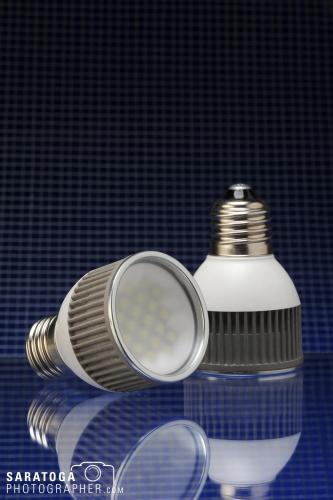 Two LED lightbulbs on gradated black to blue reflective surface